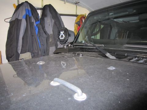 2008 Jeep Wrangler - A black Jeep Wrangler hood is visible, with a light mounted on the cowl. Jackets hang in the background.