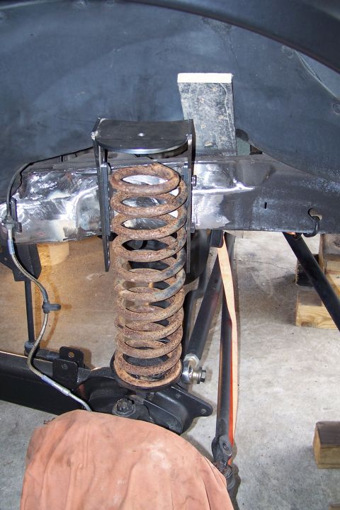 2000 Ford F-150 - Close-up of a rusty coil spring and suspension modification, with visible metalwork and a brake line.