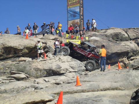 1979 Ford Bronco - An off-road buggy navigates a challenging rocky course during an event, with spectators gathered on the surrounding hills.