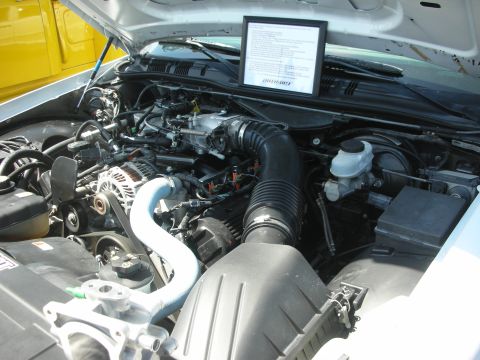 2004 Ford Crown Victoria - The engine bay of a 2004 Ford Crown Victoria is visible, with a framed document placed on the engine.