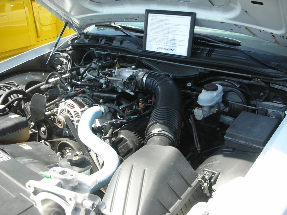 2004 Ford Crown Victoria engine bay with a framed document on top of the engine