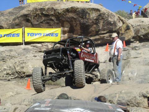 1979 Ford Bronco - A custom off-road buggy navigates a rocky obstacle course with spectators and other vehicles present.