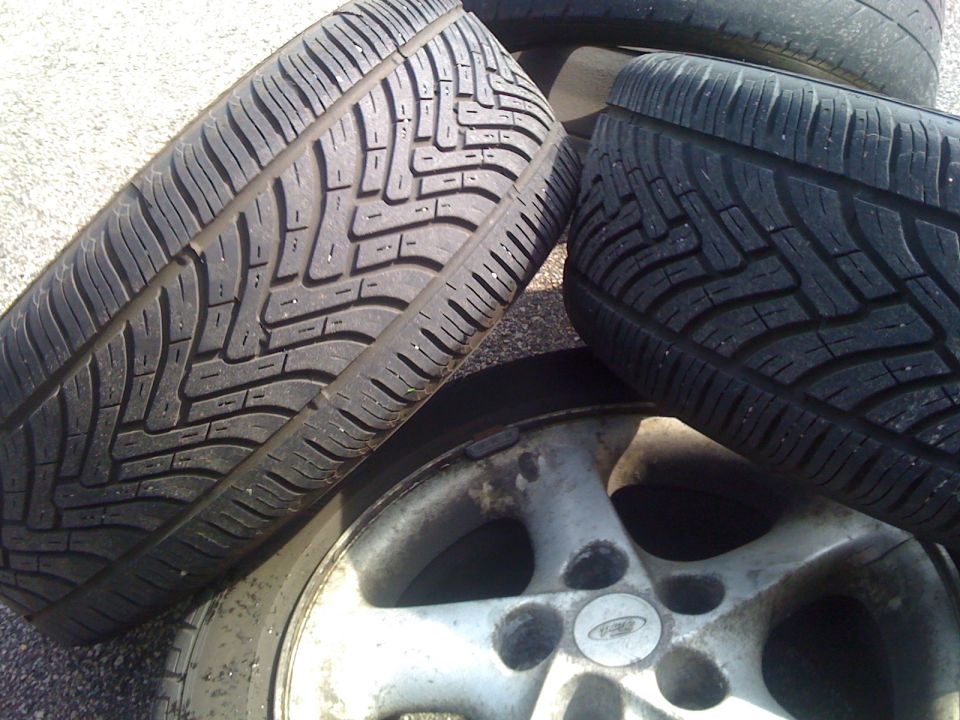 Tires stacked on a silver alloy wheel with a Ford logo