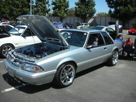 2004 Ford Crown Victoria - A silver coupe with its hood open is displayed at a car show, revealing its engine and custom modifications.