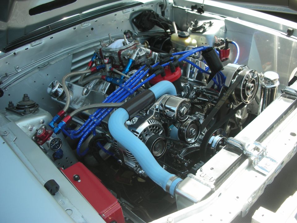 Engine bay with chrome V8 engine, blue spark plug wires, and light blue hoses