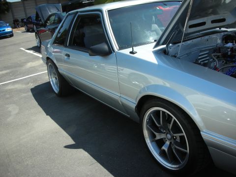 2004 Ford Crown Victoria - A silver Ford Mustang is parked in a lot with other cars, its hood open to reveal the engine.
