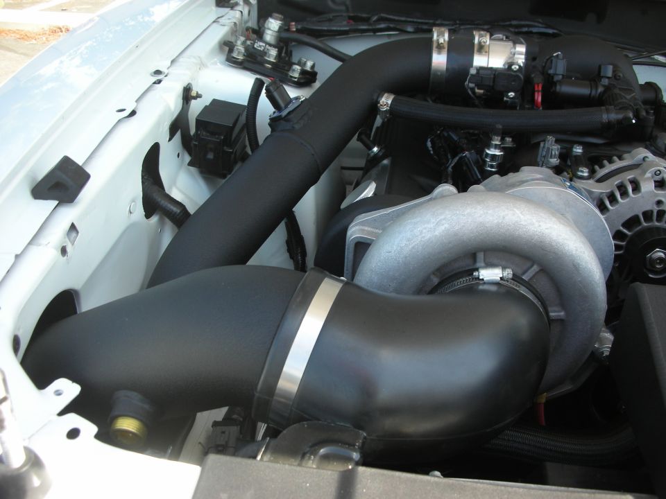 Engine bay with a supercharger and black intake piping