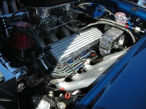 2004 Ford Crown Victoria - A highly customized V8 engine bay features chrome accents and performance parts, with a vintage Ford club sticker.