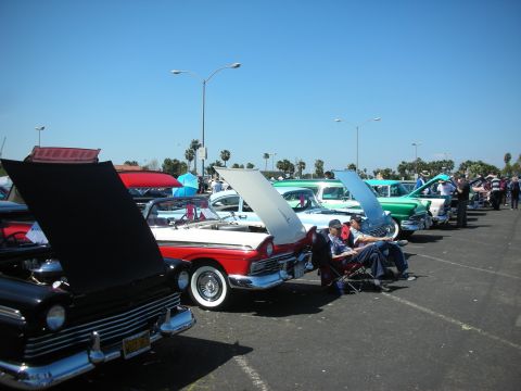 2004 Ford Crown Victoria - Classic cars are displayed with their hoods open at an outdoor car show.