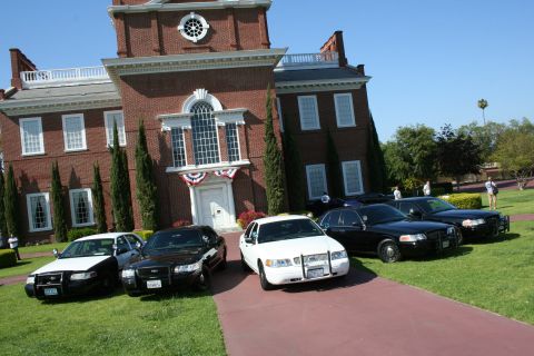 2004 Ford Crown Victoria - Several police vehicles, including a white 2004 Ford Crown Victoria, are parked on the lawn at Knott's Berry Farm.