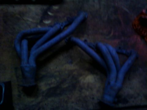 1989 Chevrolet Camaro - Two blue exhaust manifolds are shown against a dark, textured background.