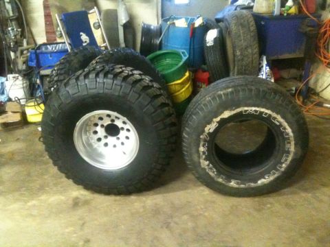 1993 Ford Bronco - A collection of off-road tires, including one mounted on a polished aluminum wheel, are stored indoors.