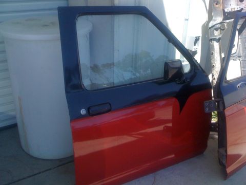 1992 Ford Ranger - A detached red and blue truck door is shown, with another door visible next to it.