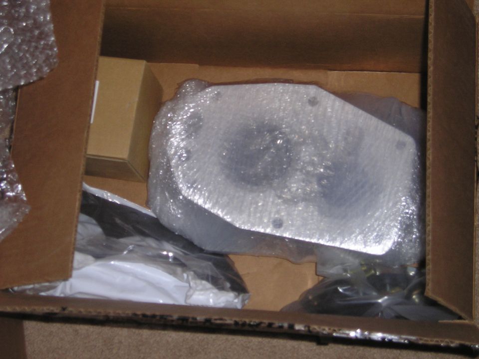 Cardboard box containing a metal suspension component wrapped in bubble wrap