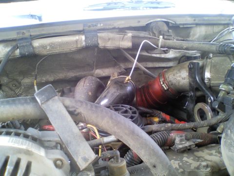 1989 Ford Bronco - Close-up view of a vehicle's engine bay, showing various hoses, pipes, and electrical components.