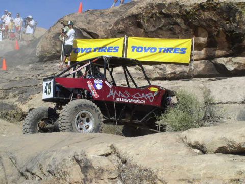 1979 Ford Bronco - A red off-road buggy navigates a rocky course, with 'Toyo Tires' banners in the background.