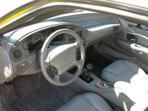 1993 Ford Taurus - The interior of a 1993 Ford Taurus shows gray leather seats and a dashboard with a prominent steering wheel.