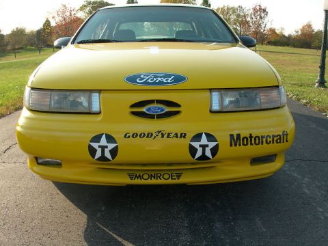 1993 Ford Taurus - Front view of a yellow 1993 Ford Taurus, adorned with various racing-themed decals.