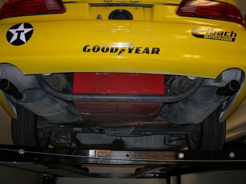 1993 Ford Taurus - The rear underside of a yellow car shows dual exhaust, a Goodyear tire, and an Eibach Springs sticker.