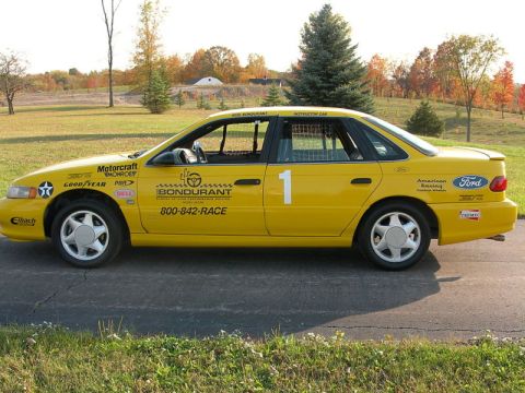 1993 Ford Taurus - This yellow 1993 Ford Taurus, likely a SHO model, is outfitted for racing with numerous sponsor decals and a prominent number 1.