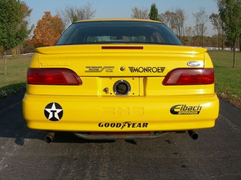 1993 Ford Taurus - Rear view of a yellow 1993 Ford Taurus SHO, showing various aftermarket decals and exhaust tips.