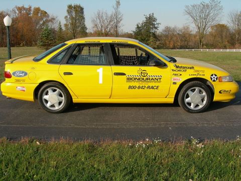 1993 Ford Taurus - A yellow sedan modified for racing, various sponsor decals and a prominent racing number.