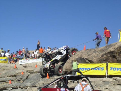 1979 Ford Bronco - A buggy navigates a steep, rocky course with spectators and support crew present.