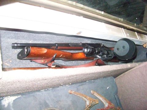 1989 Ford Bronco - A rifle with a wooden stock, scope, and drum magazine is visible on the interior of a vehicle.