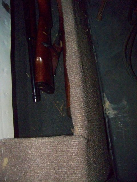 1989 Ford Bronco - A rifle stock is visible against the carpeted interior of a vehicle.