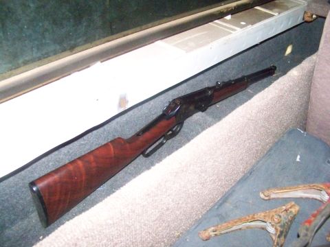 1989 Ford Bronco - Lever-action rifle with wooden stock resting on car's carpeted floor.