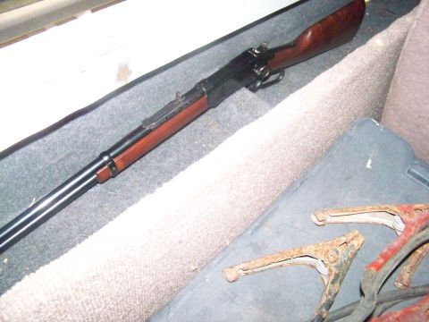1989 Ford Bronco - A rifle is placed on the floor of a vehicle, near jumper cables.