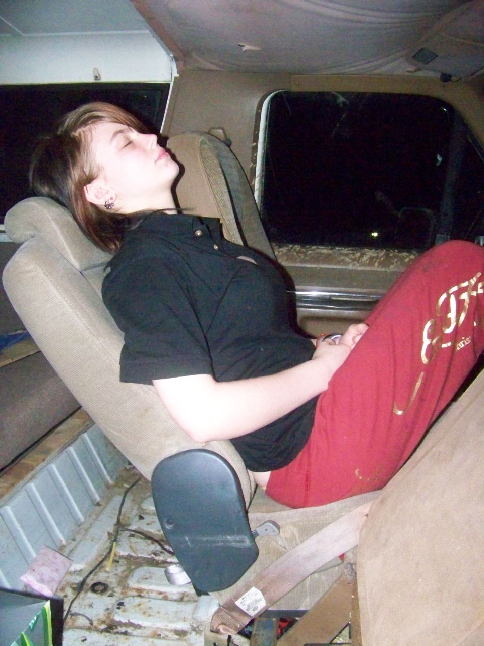 Person sleeping in the back of a vehicle, reclined on a seat