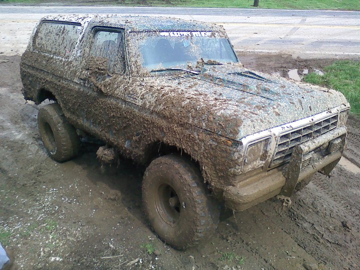 Mud-covered 1978 Ford Bronco in a muddy field, front 3/4 view