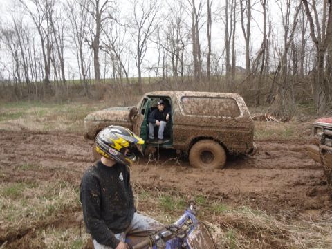 1979 Ford Bronco - This muddy SUV appears to be stuck in a field, with a dirt bike rider in the foreground.