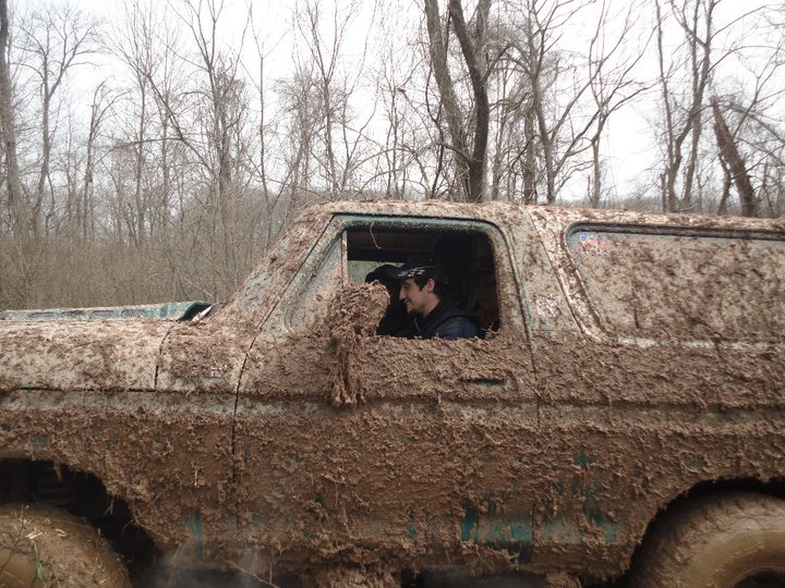Side view of a mud-covered 1979 Ford Bronco with a driver