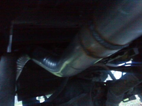 1995 Ford Bronco - This is a close-up, low-angle shot of the underside of a vehicle, focusing on the exhaust system. A bent metal pipe, likely part of the exh…