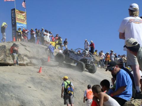 1979 Ford Bronco - A custom off-road buggy navigates a steep, dusty hillclimb course with a crowd of onlookers.