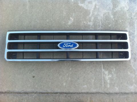 1990 Ford Bronco - A Ford grille with the blue oval emblem is shown against a concrete background.