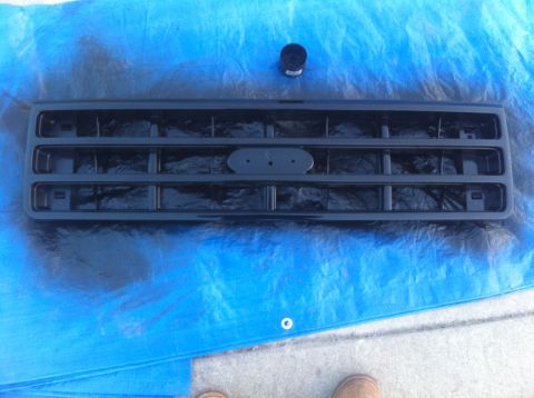1990 Ford Bronco - Grille for a 1990 Ford Bronco, placed on a blue tarp for painting.