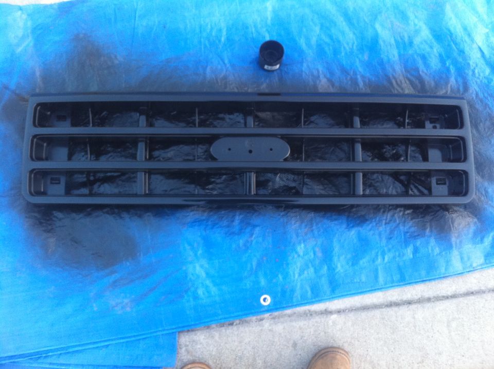 Black Ford Bronco grille with oval emblem mount, sitting on blue tarp