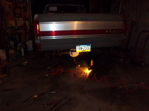 1989 Ford F-150 - The rear of a Ford F-150 truck is visible, with tools and equipment on the ground.