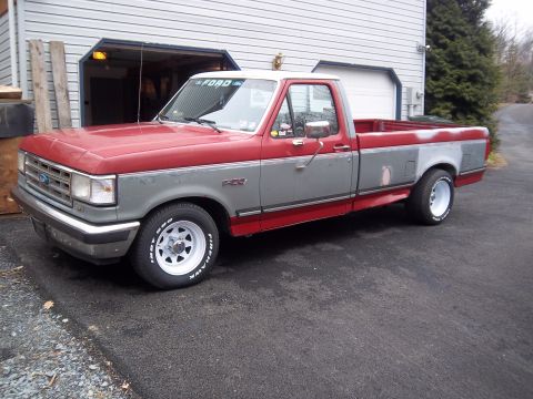 1989 Ford F-150 - This Ford F-150 pickup truck has a two-tone red and gray paint scheme and appears to be from the late 1980s.
