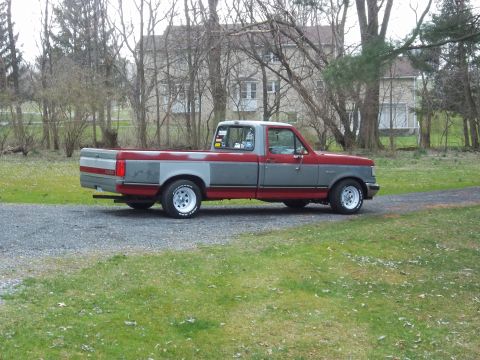 1989 Ford F-150 - This two-tone red and grey pickup truck is a 1989 Ford F-150, viewed from the side.