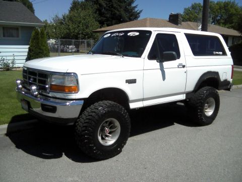 1996 Ford Bronco - White 1996 Ford Bronco with aftermarket wheels and tires, lifted suspension, parked outside.