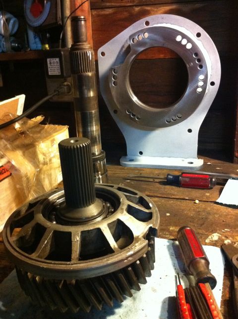 1989 Ford Bronco - Transfer case components and an adapter plate are laid out on a workbench.