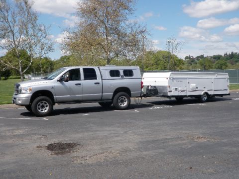 2007 Dodge 2500 - A silver 2007 Dodge 2500 pickup truck is seen from the side, towing a white pop-up camper trailer.
