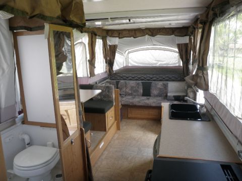 2007 Dodge 2500 - The interior of a pop-up camper shows a compact living space with a toilet, sink, and sleeping area.