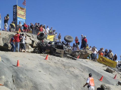 1979 Ford Bronco - A crowd watches as an off-road buggy rolls over during an event on a steep, rocky incline.