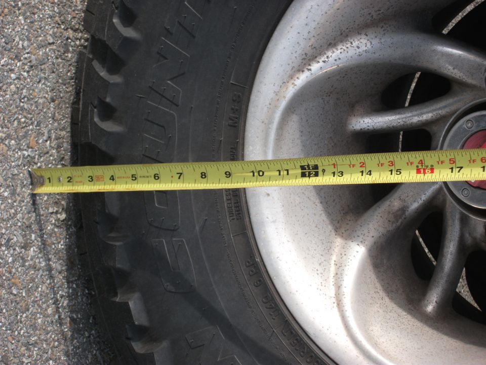 Close-up of a tire and alloy wheel with a yellow measuring tape across it