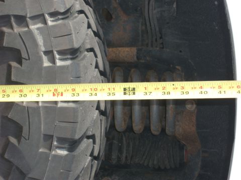 1996 Ford Bronco - Measuring tape shows tire diameter next to suspension coil and bracket.